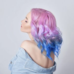 Portrait of a woman with bright colored flying hair, all shades of purple. Hair coloring, beautiful lips and makeup. Hair fluttering in the wind. Sexy girl with short  hair. Professional coloring